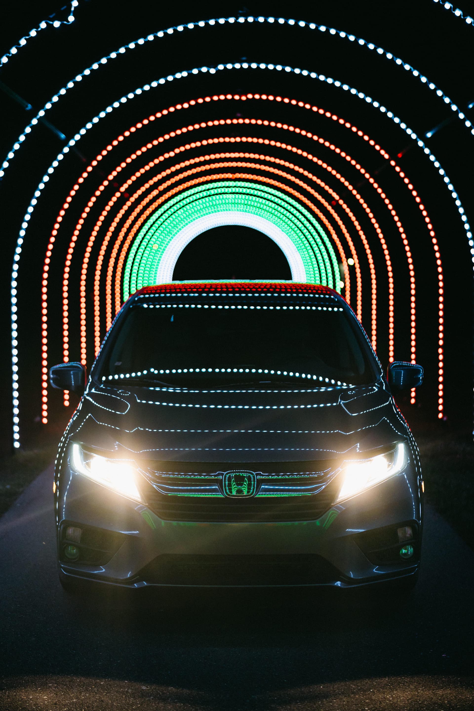 Car driving through spectacular LED light tunnel with rainbow arcs